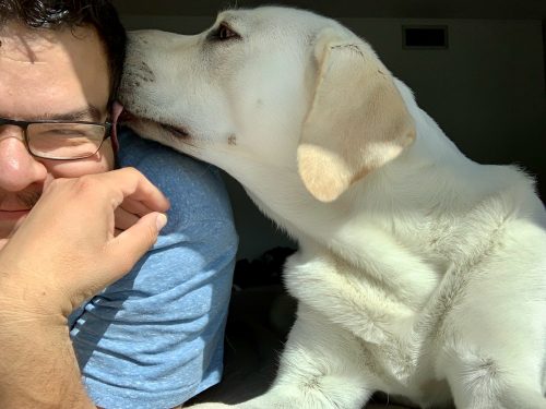 Angel Villalobos with his dog giving him a kiss
