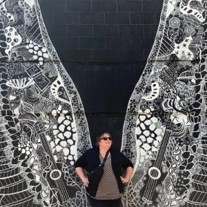 Jen Wilkins in front of a black and white mural of angel wings