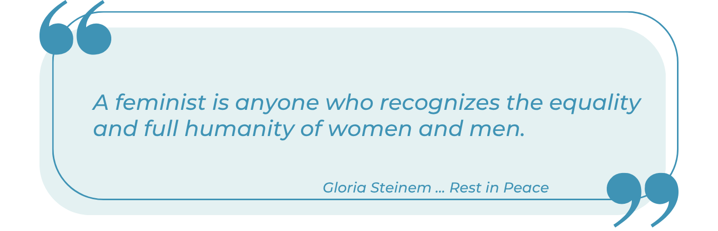 A stylized quote graphic with a light blue rounded rectangle background bordered by a teal outline and large quotation marks in the top-left and bottom-right corners. The italicized teal text reads: 'A feminist is anyone who recognizes the equality and full humanity of women and men.' Below the quote, in smaller italic text, is the attribution 'Gloria Steinem … Rest in Peace,' indicating a memorial tribute to the feminist author and activist.