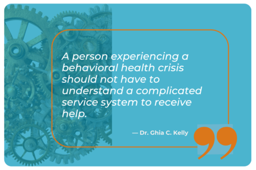 A teal blue graphic features an orange-outlined rounded rectangle containing an italicized white quote attributed to Dr. Ghia C. Kelly, reading 'A person experiencing a behavioral health crisis should not have to understand a complicated service system to receive help.' A large orange quotation mark sits at the bottom right corner. In the background, a faded overlay of interlocking mechanical gears spans the left portion of the image, symbolizing the complexity of service systems being addressed.