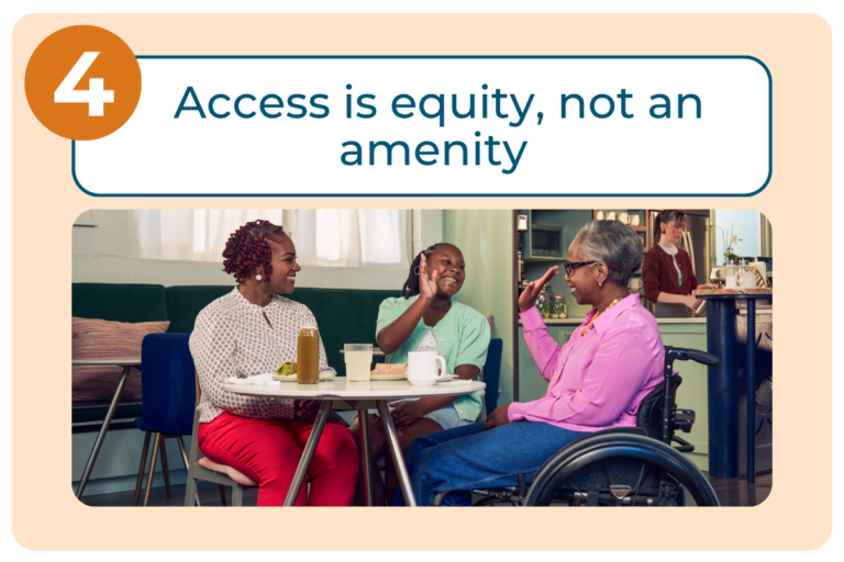 An orange number 4 icon sits beside a white banner reading 'Access is equity, not an amenity' in dark teal text. Below, a photo shows a woman, a child, and an older woman using a wheelchair gathered around a small table in a kitchen, exchanging a high-five and smiling together. A person in the background works at a kitchen counter, reinforcing a warm, everyday home setting that illustrates accessibility as a natural part of daily life rather than an added extra.