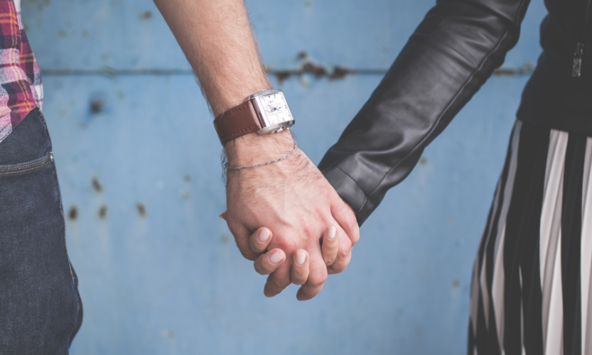 A close-up shot of two people holding hands.