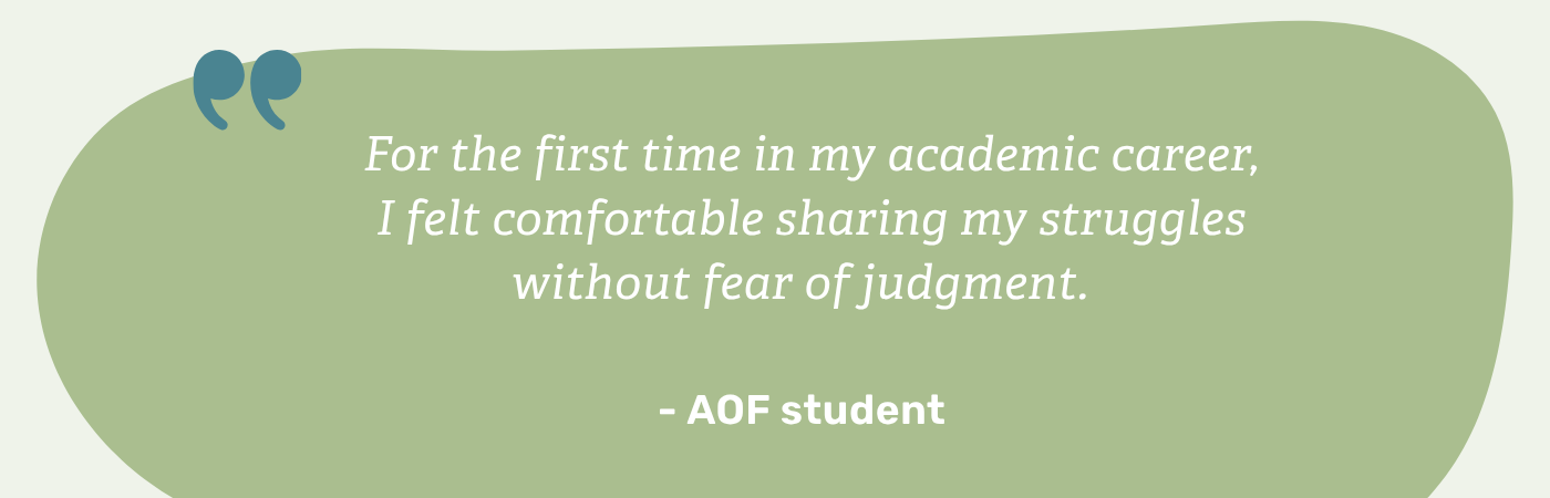 A testimonial quote centered on a soft, sage-green organic shape with large, dark-teal quotation marks in the top-left corner. The white text reads, "For the first time in my academic career, I felt comfortable sharing my struggles without fear of judgment." The quote is attributed to an AOF student.