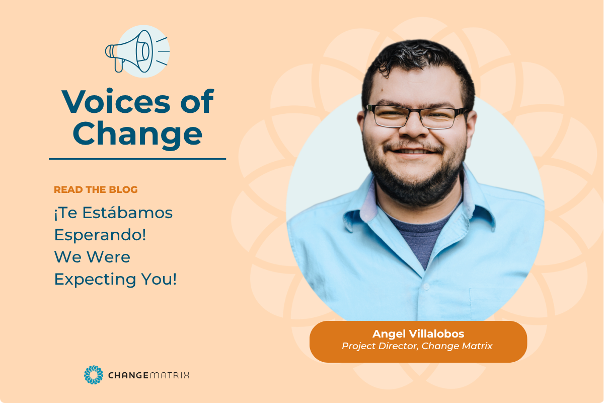 A promotional graphic on a peach background for Change Matrix's 'Voices of Change' blog series. On the left, a megaphone icon sits above the bold heading 'Voices of Change,' followed by the label 'READ THE BLOG' in orange and the bilingual blog title 'Te Estabamos Esperando! We Were Expecting You!' in dark blue text. On the right, a circular photo shows a smiling man with short dark hair, a beard, and glasses, wearing a light blue button-up shirt over a navy t-shirt. Below his photo, an orange rounded rectangle identifies him as 'Angel Villalobos, Project Director, Change Matrix.' The Change Matrix logo, a small circular flower-like icon with the wordmark 'CHANGEMATRIX,' appears in the bottom left corner, and a faint floral pattern decorates the background behind the portrait.