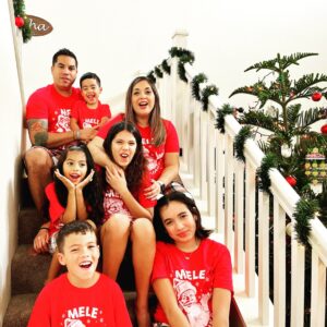 Cindy and family celebrating the holidays wearing matching red and white t-shirts on a decorative staircase.