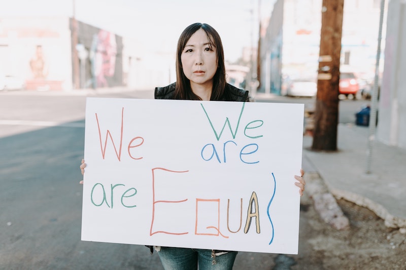Woman holds a sign that says "we are equal."